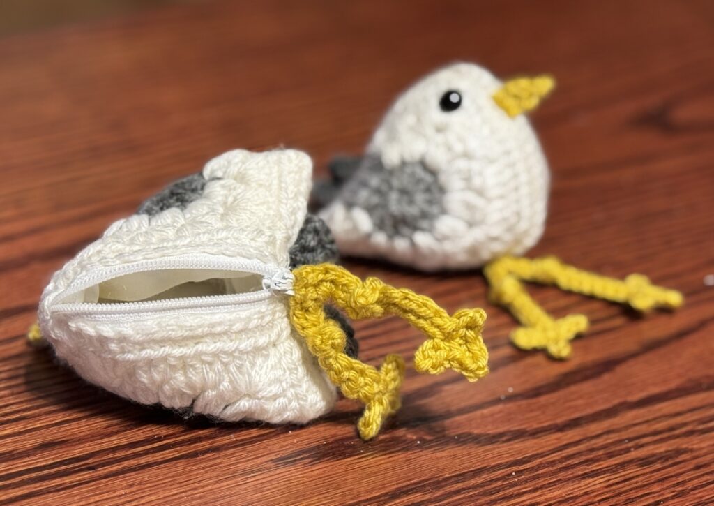 seagull made from two crochet granny squares. One as a zipper pouch with feet attached to zipper pull.